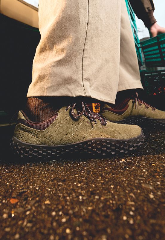 A person wearing olive green Merrell barefoot shoes.
